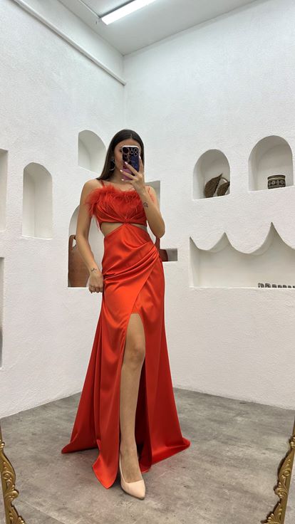 Vestido de noche naranja de satén con tirantes y detalle de plumas en la cintura 