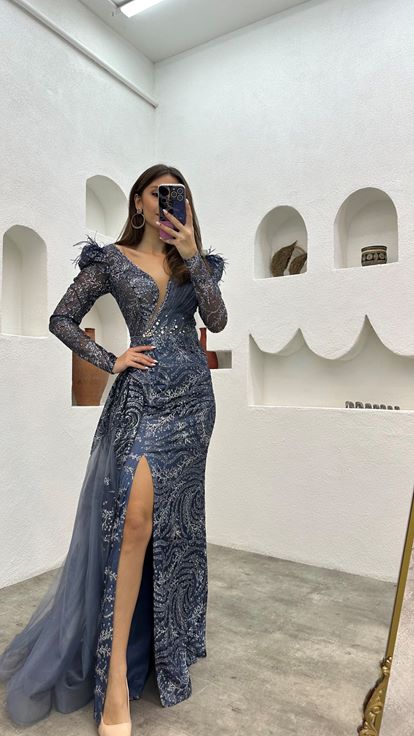 فستان سهرة من التول باللون الأزرق الداكن مزين بتفاصيل من الريش المطرز