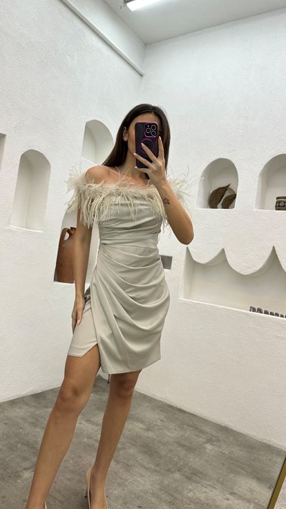 فستان سهرة من الساتان البيج مزين بتفاصيل من الريش ومُكشكش