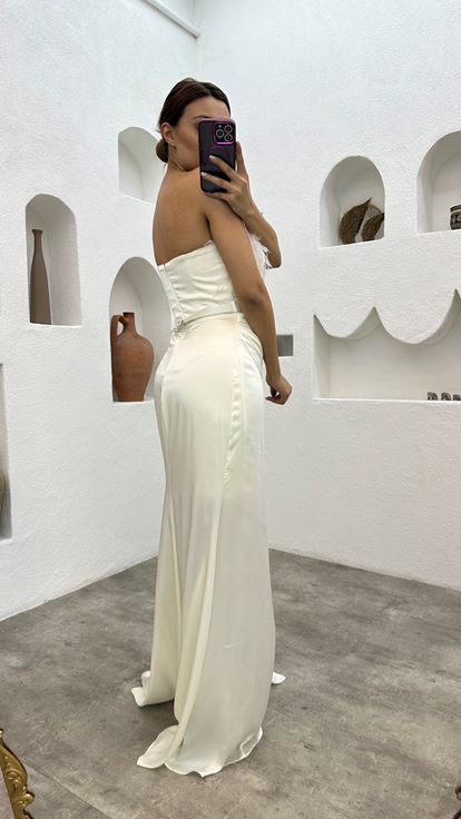 فستان سهرة أبيض من الساتان مزين بتفاصيل من الريش وحزام منسدل