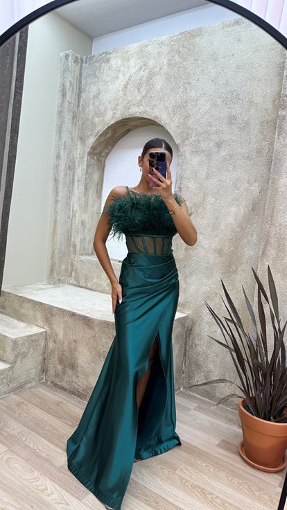 Vestido de noche de satén verde esmeralda con tirantes y detalle de plumas en el busto y la cintura 
