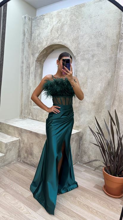 Vestido de noche de satén verde esmeralda con tirantes y detalle de plumas en el busto y la cintura 