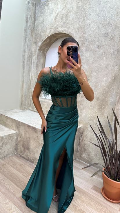 Vestido de noche de satén verde esmeralda con tirantes y detalle de plumas en el busto y la cintura 