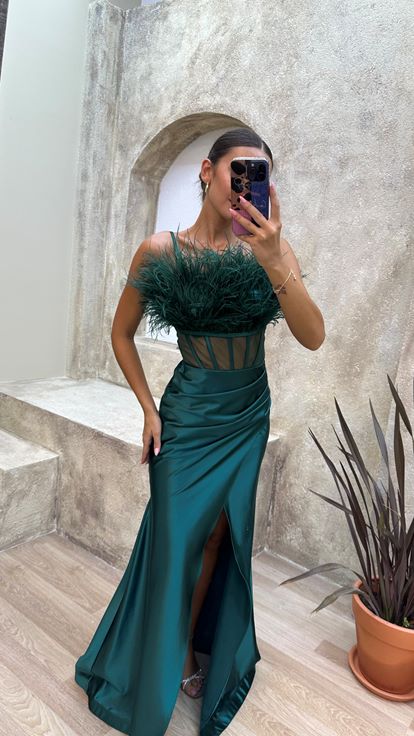 Vestido de noche de satén verde esmeralda con tirantes y detalle de plumas en el busto y la cintura 