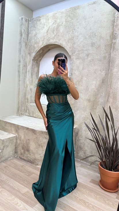 Vestido de noche de satén verde esmeralda con tirantes y detalle de plumas en el busto y la cintura 
