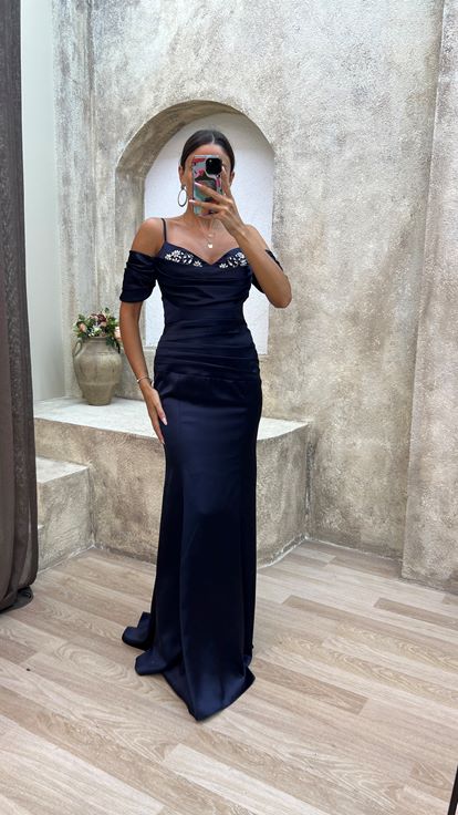 فستان سهرة من الساتان المطرز باللون الأزرق الداكن، بأكمام مكشكشة وتفاصيل أنيقة 