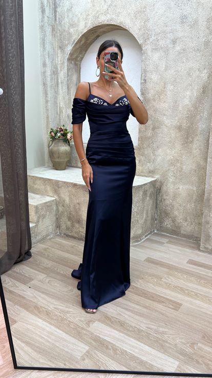 فستان سهرة من الساتان المطرز باللون الأزرق الداكن، بأكمام مكشكشة وتفاصيل أنيقة 