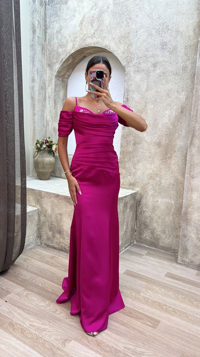 فستان سهرة من الساتان المطرز بلون الفوشيا، بأكمام مزينة بأشرطة وتفاصيل منسدلة 