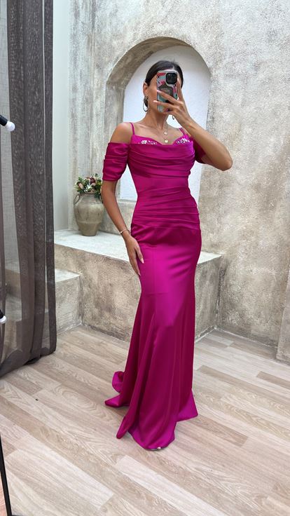 فستان سهرة من الساتان المطرز بلون الفوشيا، بأكمام مزينة بأشرطة وتفاصيل منسدلة 