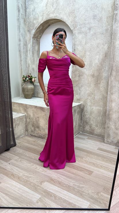 فستان سهرة من الساتان المطرز بلون الفوشيا، بأكمام مزينة بأشرطة وتفاصيل منسدلة 