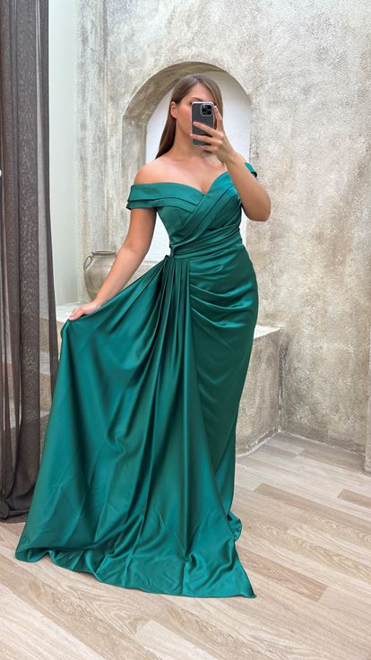 فستان سهرة أخضر من الساتان بمقاسات كبيرة، بياقة قارب وتفاصيل عند الخصر 