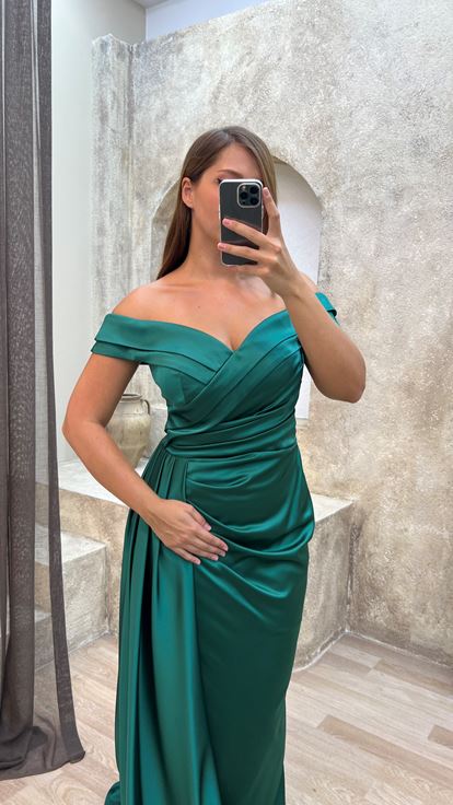 فستان سهرة أخضر من الساتان بمقاسات كبيرة، بياقة قارب وتفاصيل عند الخصر 
