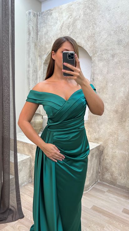 فستان سهرة أخضر من الساتان بمقاسات كبيرة، بياقة قارب وتفاصيل عند الخصر 