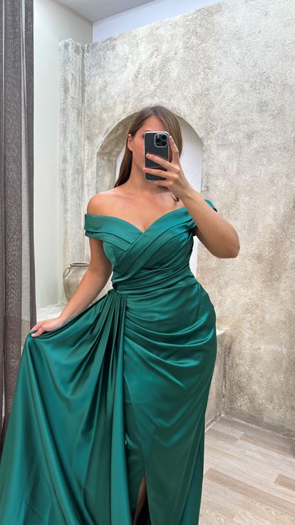 فستان سهرة أخضر من الساتان بمقاسات كبيرة، بياقة قارب وتفاصيل عند الخصر 