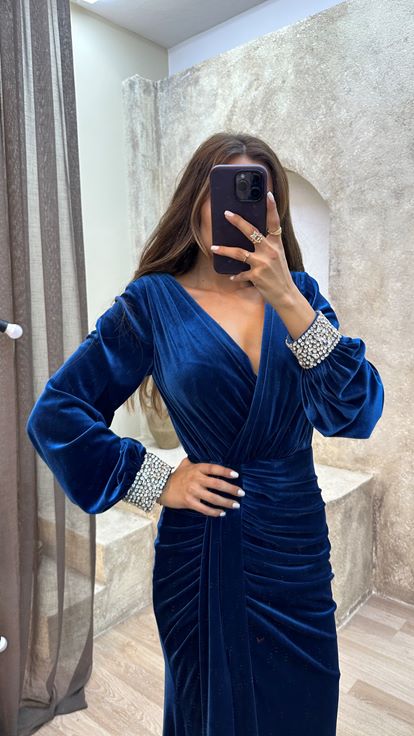 فستان أزرق داكن بياقة على شكل حرف V مع تفاصيل في الخلف وأكمام مزينة بالأحجار