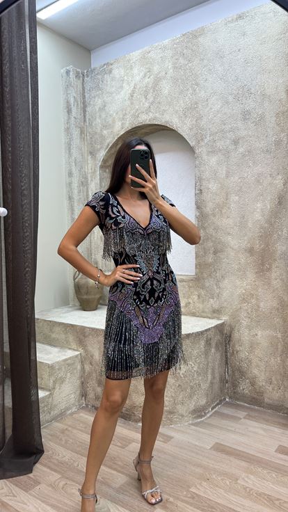 فستان أسود مزين بشراشيب في الجزء العلوي والتنورة، بتصميم مطرز مميز 