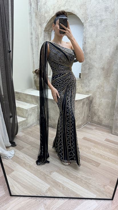 فستان سهرة أسود مطرز بتصميم خاص، بكتف واحد وأكمام واسعة 