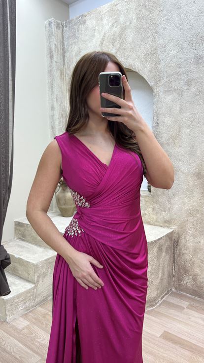 فستان سهرة وردي اللون بمقاسات كبيرة وفتحة رقبة على شكل حرف V، مزين بأحجار عند الخصر