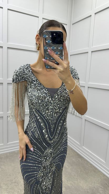 فستان سهرة رمادي بياقة على شكل حرف V مزين بشرابة على الكتفين وتصميم تطريز مميز