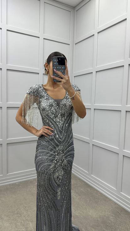 Robe de soirée grise avec détail au niveau de la poitrine  manches à pompons et broderie spéciale 