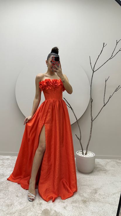 Vestido de noche naranja con detalle floral en el busto 