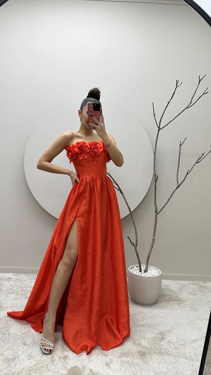 Vestido de noche naranja con detalle floral en el busto 