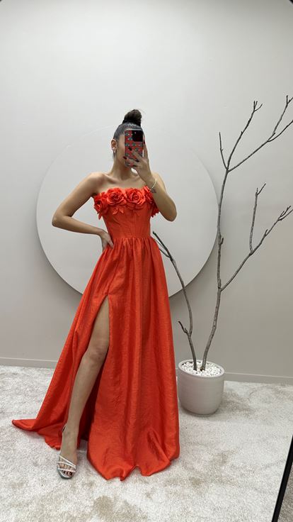Vestido de noche naranja con detalle floral en el busto 