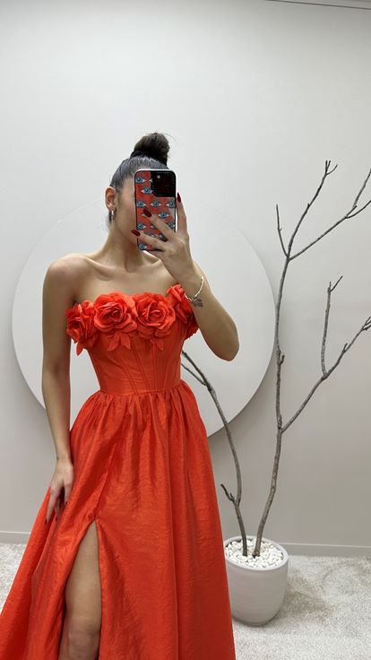 Vestido de noche naranja con detalle floral en el busto 