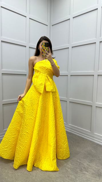 Vestido de noche amarillo con detalle de lazo de un hombro con diseño jacquard