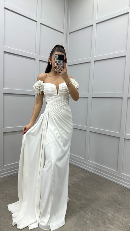 فستان سهرة أبيض بأكتاف وردية، وخصر متقاطع، وتفاصيل شفافة 