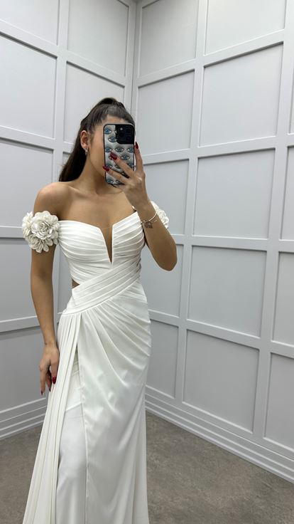 فستان سهرة أبيض بأكتاف وردية، وخصر متقاطع، وتفاصيل شفافة 