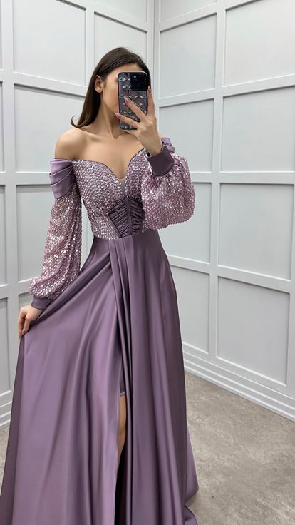 فستان سهرة من الساتان بلون وردي فاتح، بأكمام واسعة على الصدر وتفاصيل ترتر على الكتفين