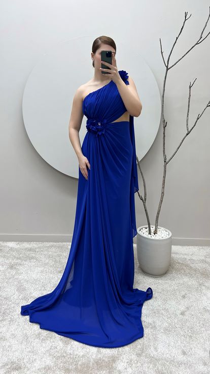 فستان سهرة من ساكس بمقاسات كبيرة بكتف واحد وتفاصيل وردة عند الخصر والكتف