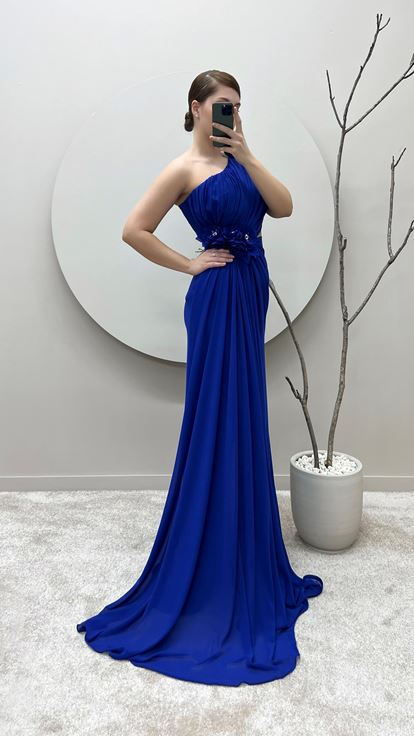 فستان سهرة من ساكس بمقاسات كبيرة بكتف واحد وتفاصيل وردة عند الخصر والكتف