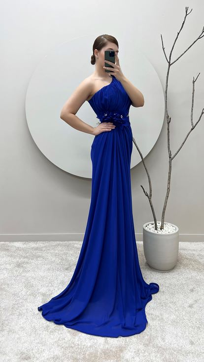 فستان سهرة من ساكس بمقاسات كبيرة بكتف واحد وتفاصيل وردة عند الخصر والكتف