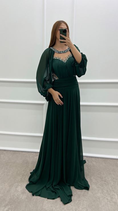 فستان أخضر زمردي بمقاسات كبيرة، صدر شفاف وأكمام واسعة، مزين بأحجار الراين 