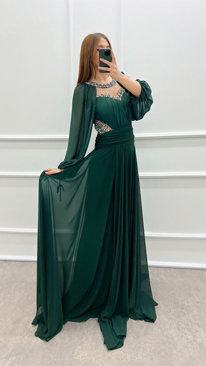 فستان أخضر زمردي بمقاسات كبيرة، صدر شفاف وأكمام واسعة، مزين بأحجار الراين 