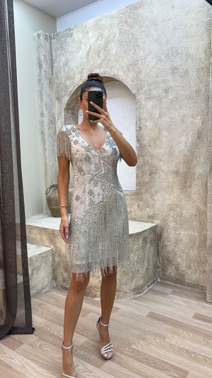 فستان أبيض بتفاصيل خلفية، مزين بتطريز خاص وتصميم مزين بشراشيب