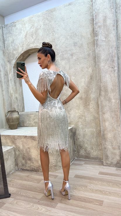 فستان أبيض بتفاصيل خلفية، مزين بتطريز خاص وتصميم مزين بشراشيب