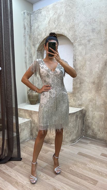 فستان أبيض بتفاصيل خلفية، مزين بتطريز خاص وتصميم مزين بشراشيب