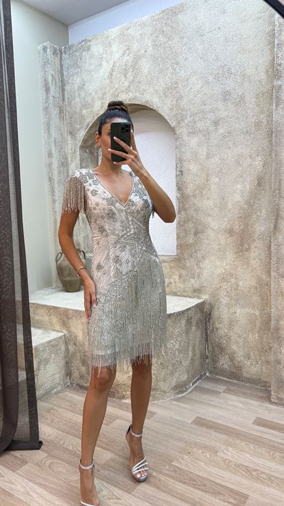 فستان أبيض بتفاصيل خلفية، مزين بتطريز خاص وتصميم مزين بشراشيب