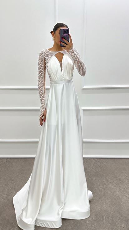 فستان أبيض من الساتان مزين بكسرات عند الصدر وأحجار مرصعة