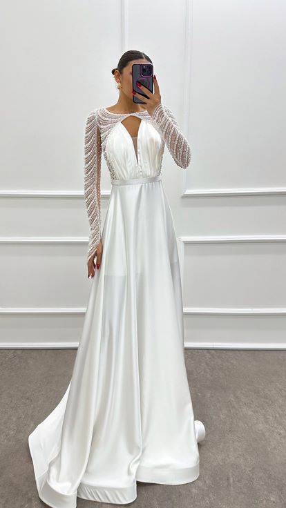 فستان أبيض من الساتان مزين بكسرات عند الصدر وأحجار مرصعة
