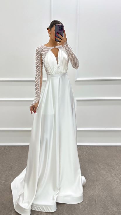 فستان أبيض من الساتان مزين بكسرات عند الصدر وأحجار مرصعة