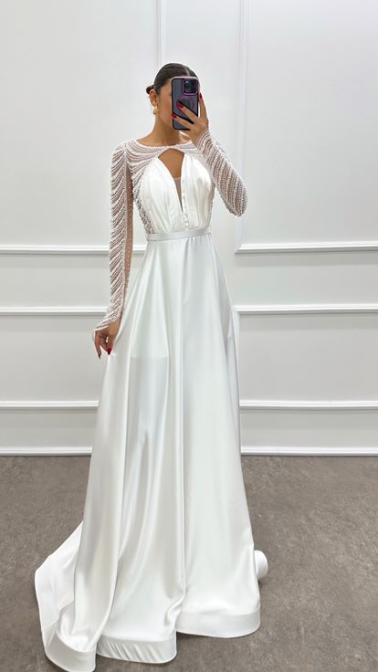 فستان أبيض من الساتان مزين بكسرات عند الصدر وأحجار مرصعة