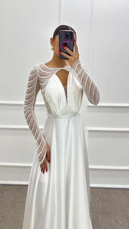 فستان أبيض من الساتان مزين بكسرات عند الصدر وأحجار مرصعة