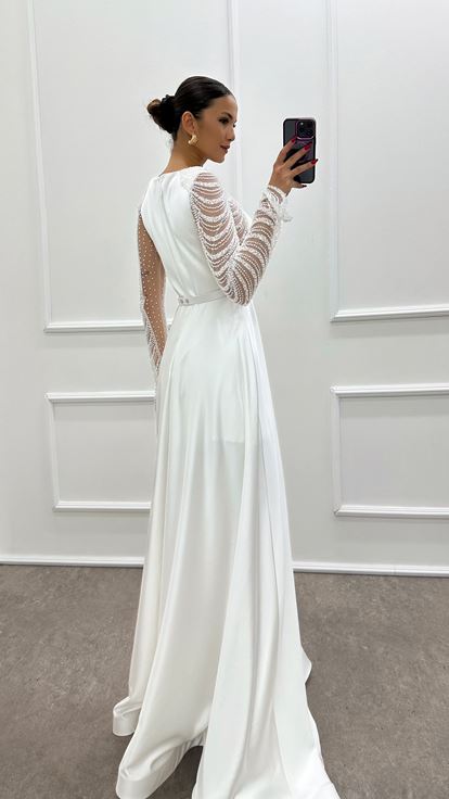 فستان أبيض من الساتان مزين بكسرات عند الصدر وأحجار مرصعة