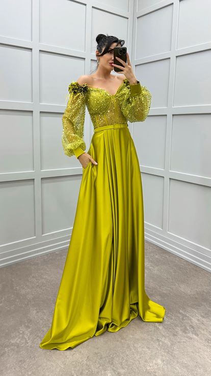 فستان أخضر بكتفين مزين بتفاصيل وردة وفستان سهرة من الساتان الشفاف المزين بالريش