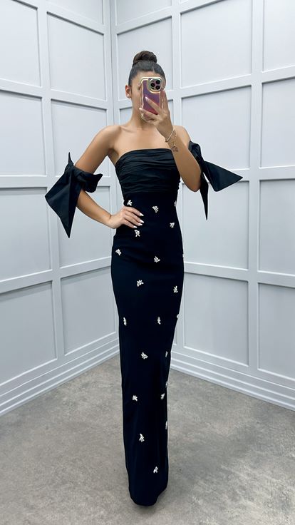 فستان أسود بدون حمالات بتفاصيل على الأكمام ومزين بأحجار الراين