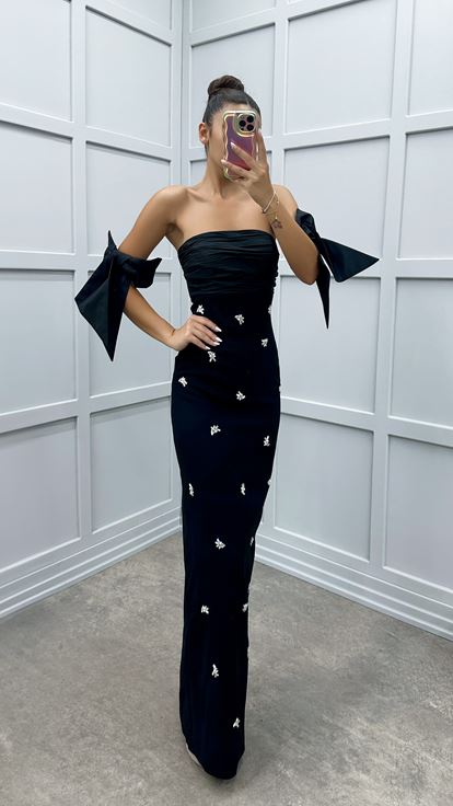 فستان أسود بدون حمالات بتفاصيل على الأكمام ومزين بأحجار الراين